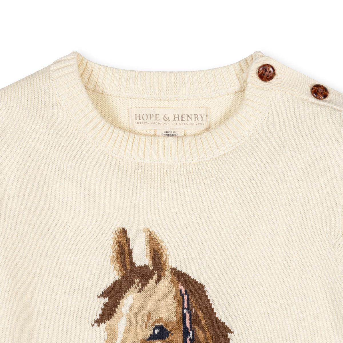 Close-up of a cream-colored knit sweater by Hope & Henry, featuring a brown and beige horse face graphic on the front and brown decorative buttons on the shoulder.