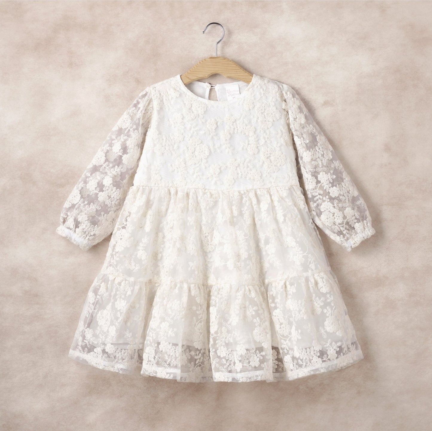 White lace dress on a hanger against a beige background