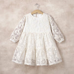 White lace dress on a hanger against a beige background