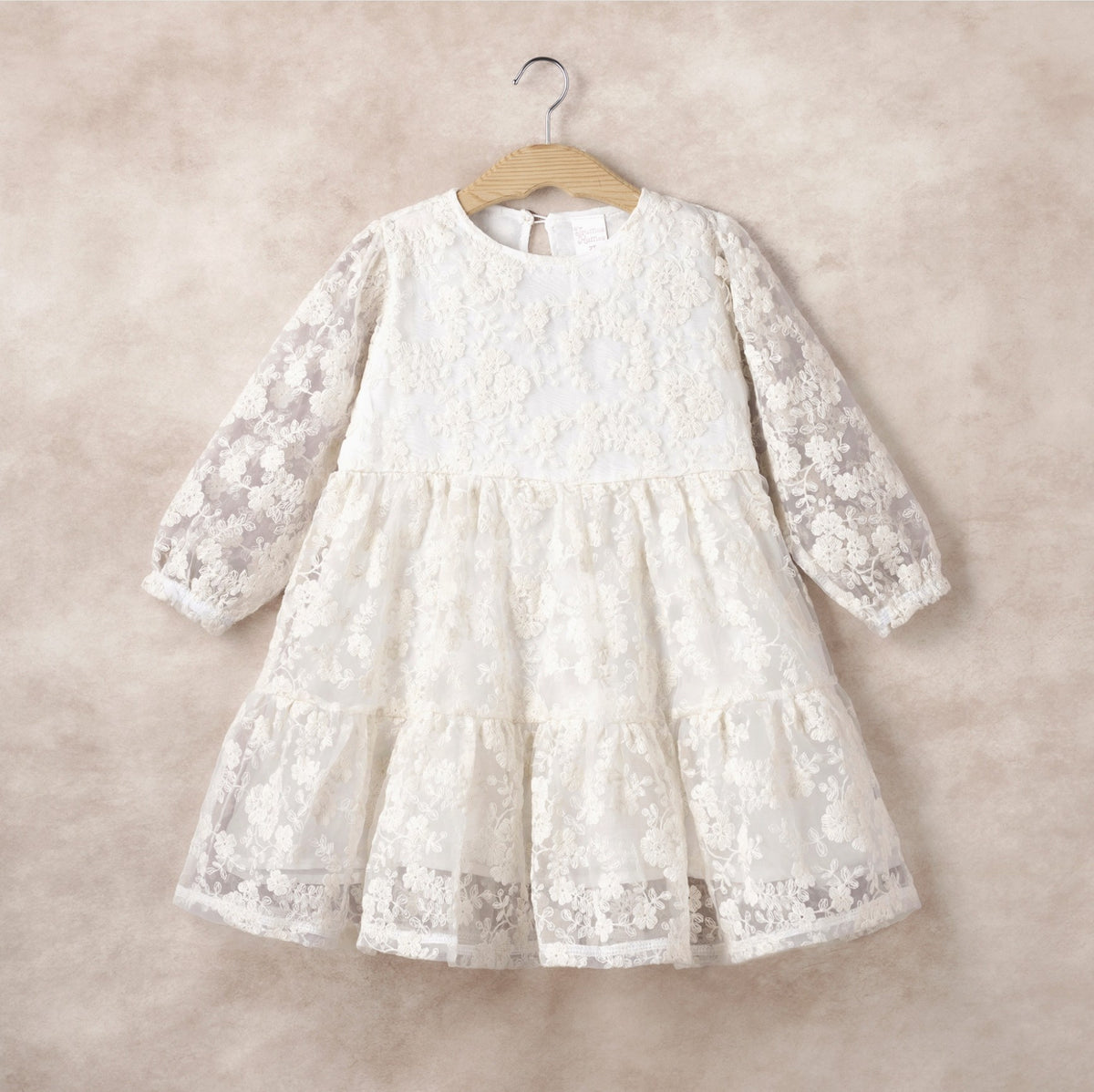 White lace dress on a hanger against a beige background