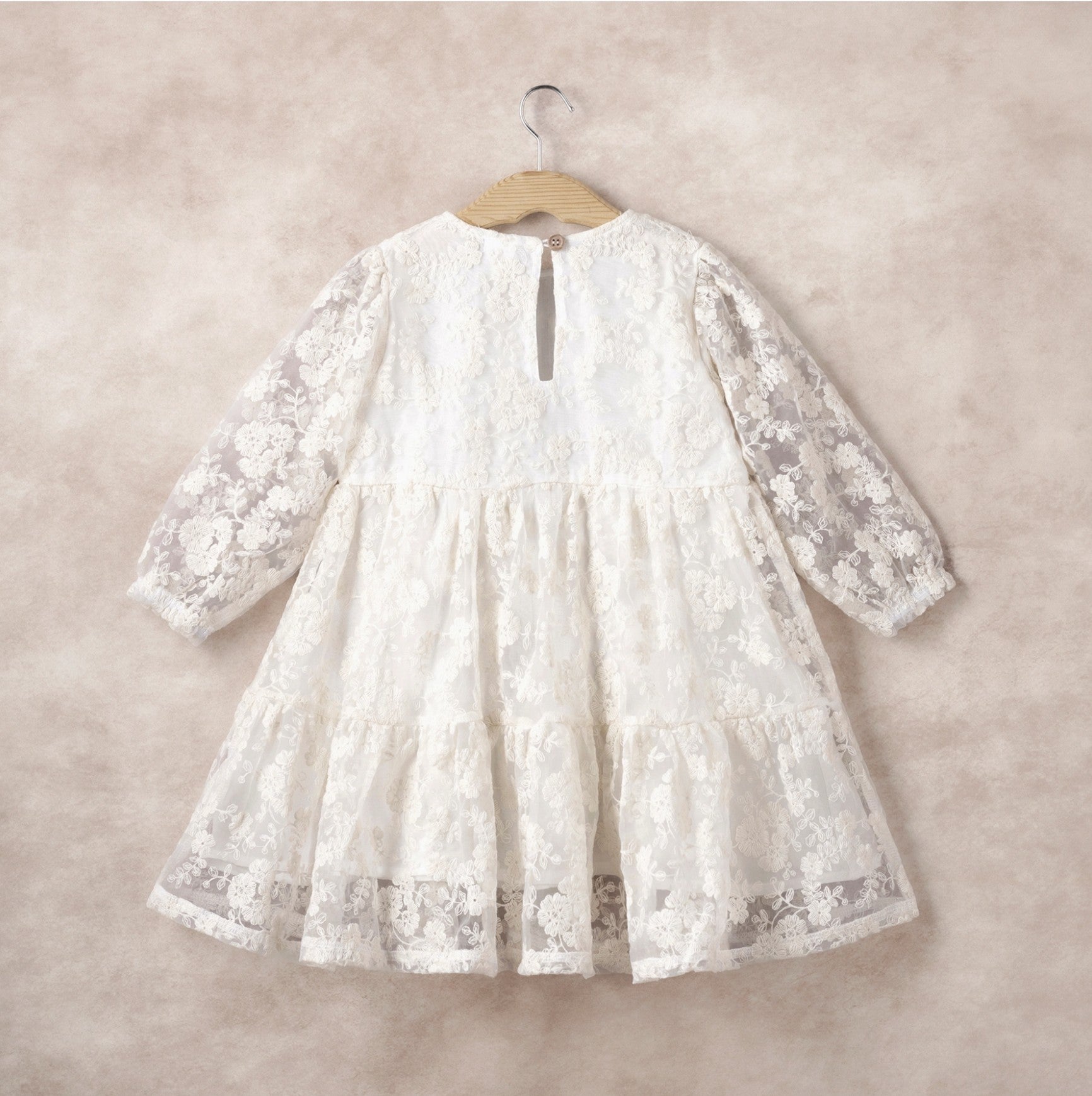 White lace dress on a hanger against a beige background