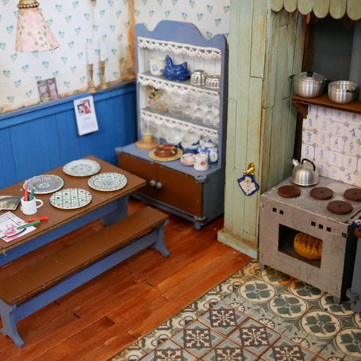 Miniature kitchen setup with a table, shelves, and stove.