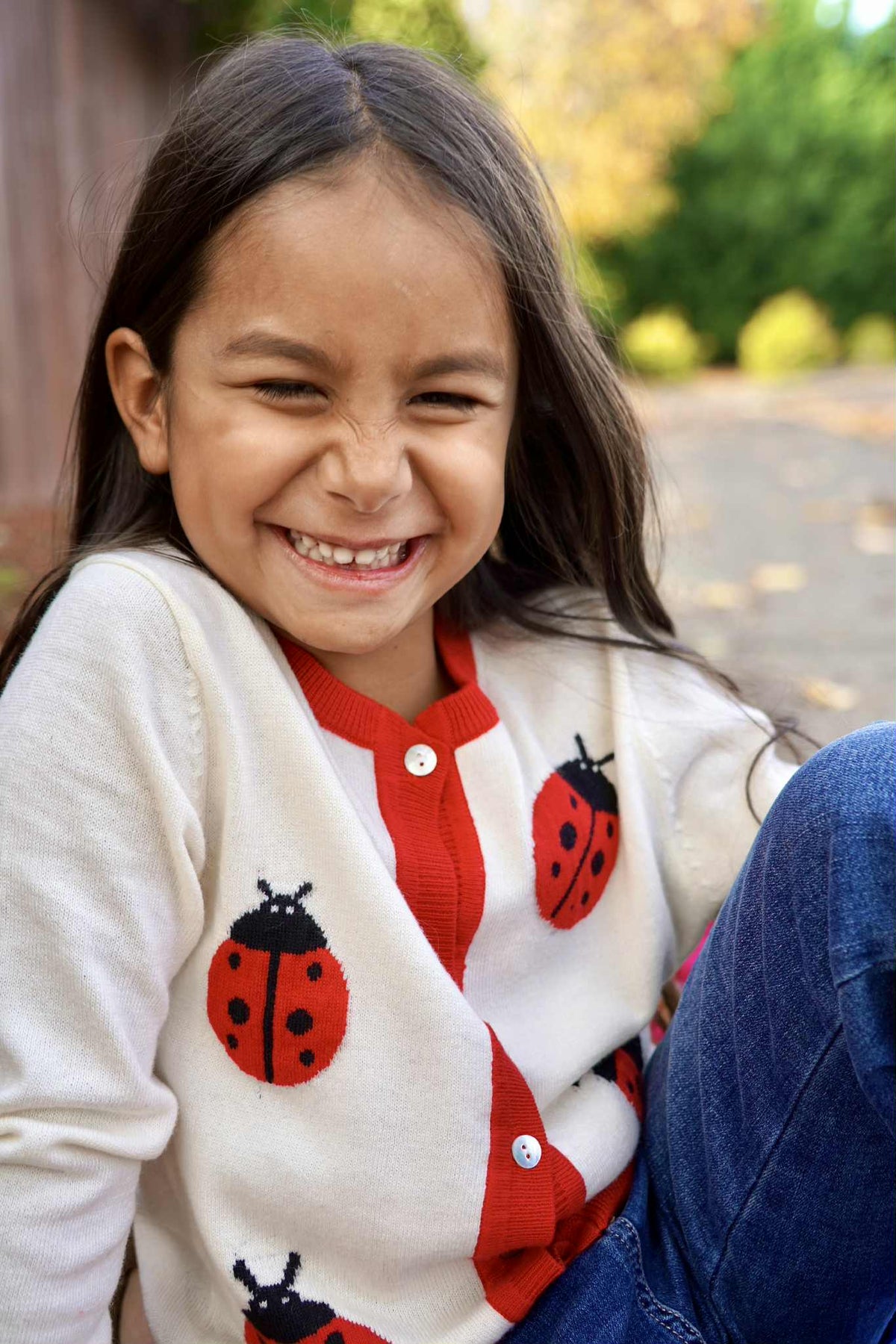 Child wearing a cardigan with ladybug patterns outdoors