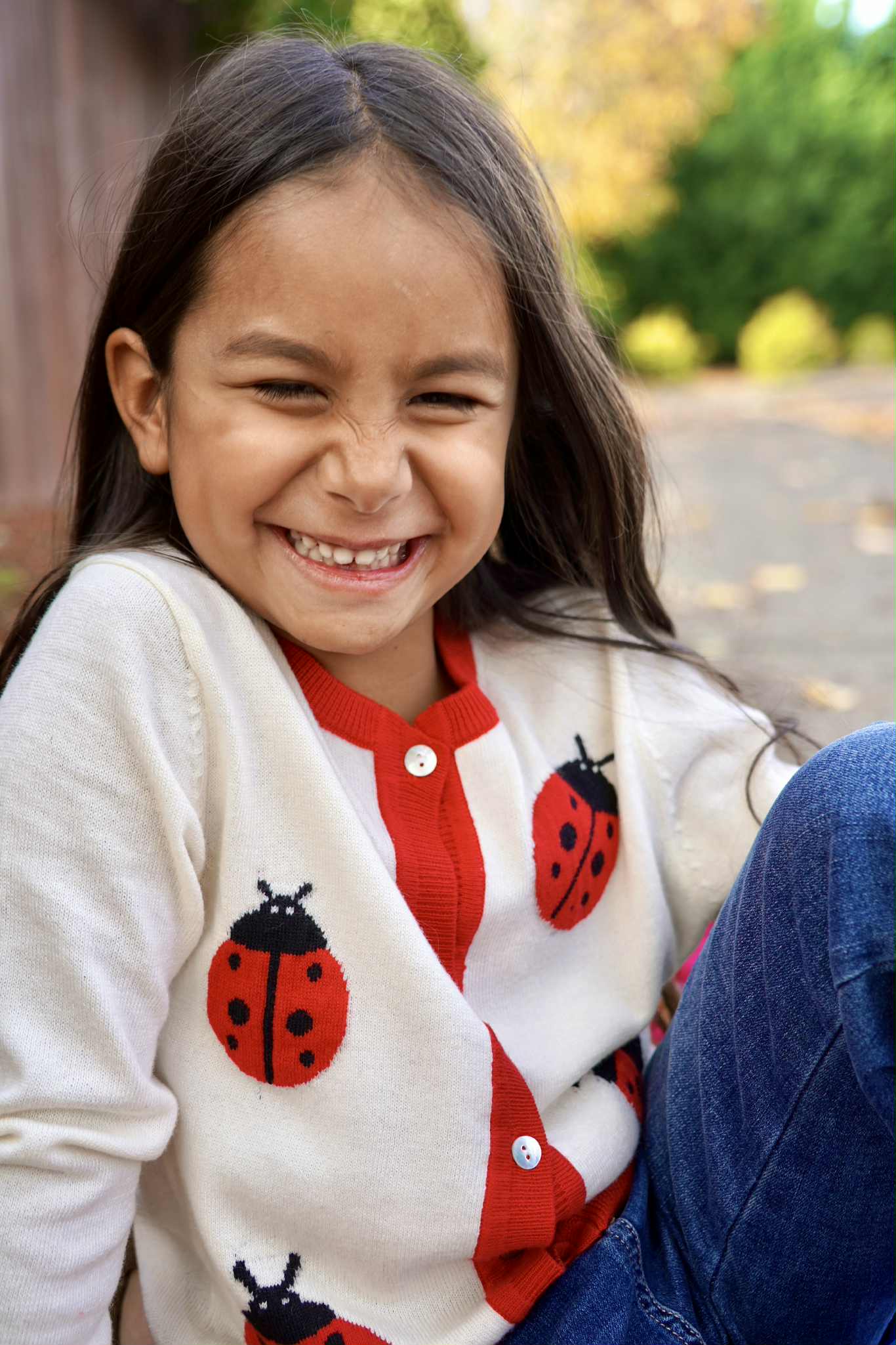 Child wearing a cardigan with ladybug patterns outdoors