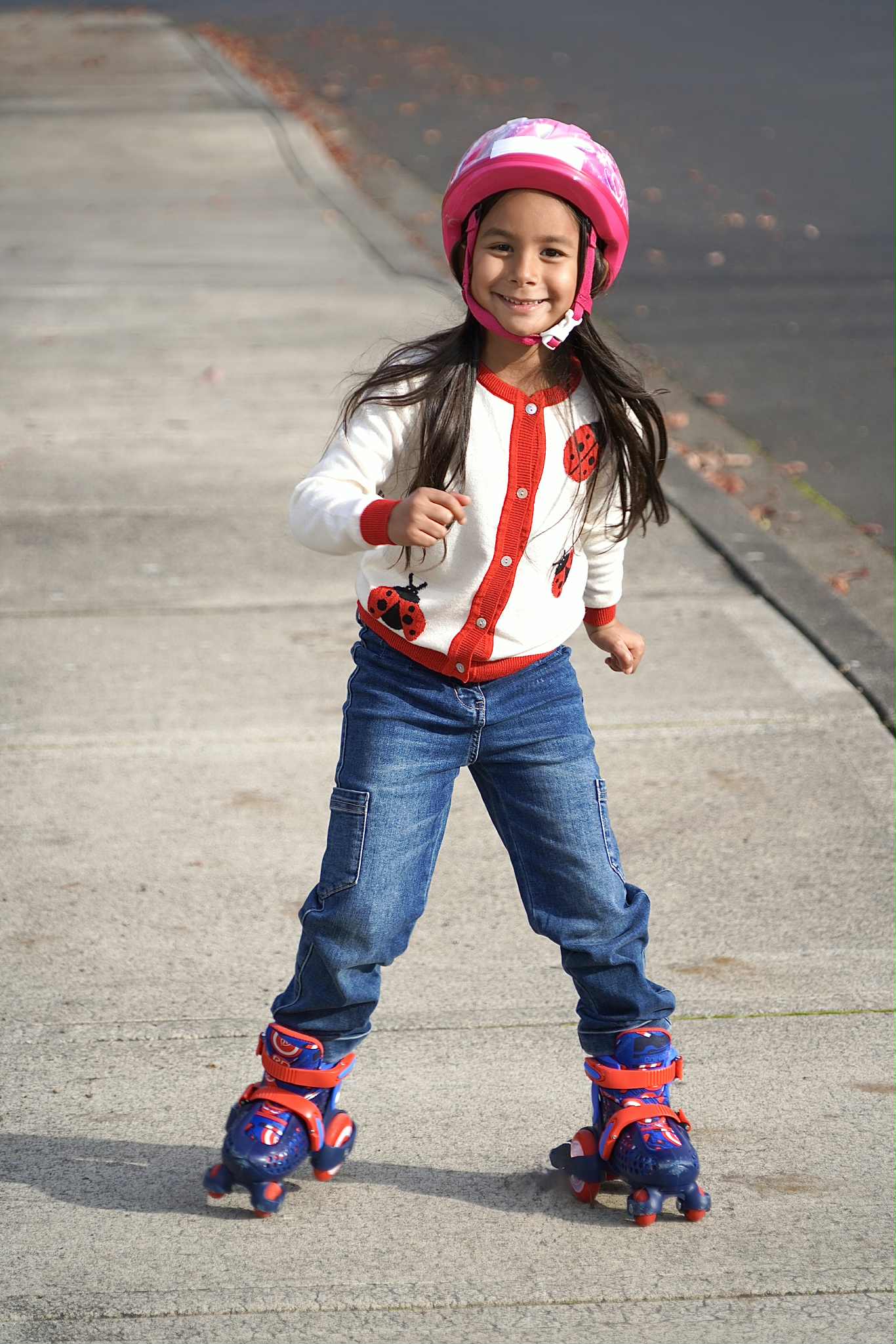 Child wearing roller skates and a helmet on a sidewalk
