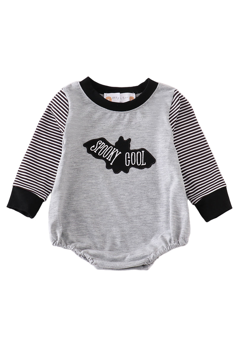 A gray baby bubble romper with black stripes on the sleeves and a graphic text 'SPOKY COOL' on the front.