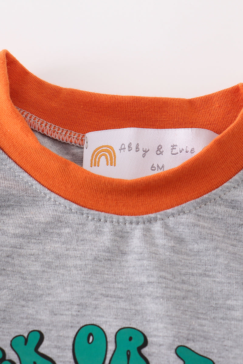 Close-up of a baby outfit with orange collar and brand label on a light background