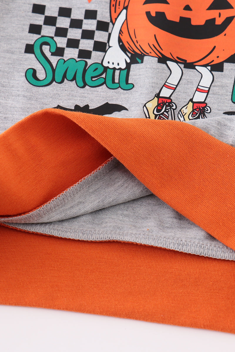 Close-up of Halloween-themed fabric with orange, gray, and black design.