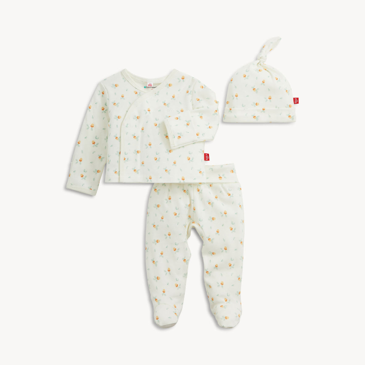 A three-piece baby clothing set including a long-sleeve wrap top, footed pants, and a knotted beanie hat, all in a soft off-white fabric with a tiny yellow and orange acorn print, shown on a light gray background.