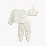 A three-piece baby clothing set including a long-sleeve wrap top, footed pants, and a knotted beanie hat, all in a soft off-white fabric with a tiny yellow and orange acorn print, shown on a light gray background.
