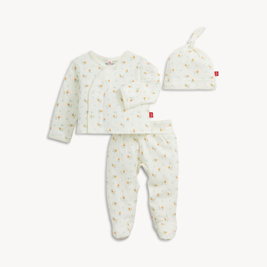 A three-piece baby clothing set including a long-sleeve wrap top, footed pants, and a knotted beanie hat, all in a soft off-white fabric with a tiny yellow and orange acorn print, shown on a light gray background.