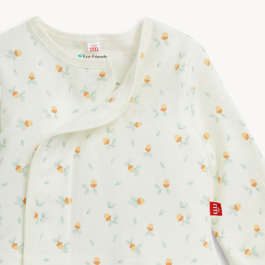 A close-up of a baby long-sleeve wrap blanket or sleep sack in off-white, featuring a delicate all-over print of small acorns and light green leaves. The brand tag 'MM' is visible on the sleeve, and an interior neck label reads 'Eco Friendly'.