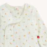 A close-up of a baby long-sleeve wrap blanket or sleep sack in off-white, featuring a delicate all-over print of small acorns and light green leaves. The brand tag 'MM' is visible on the sleeve, and an interior neck label reads 'Eco Friendly'.
