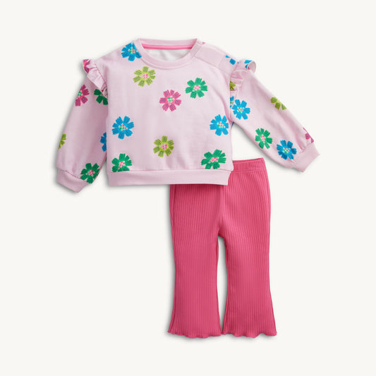 A toddler girl's two-piece outfit set featuring a light pink long-sleeve sweatshirt with colorful floral patterns and ruffled shoulder details, paired with bright pink ribbed flare pants, shown on a clean off-white background.