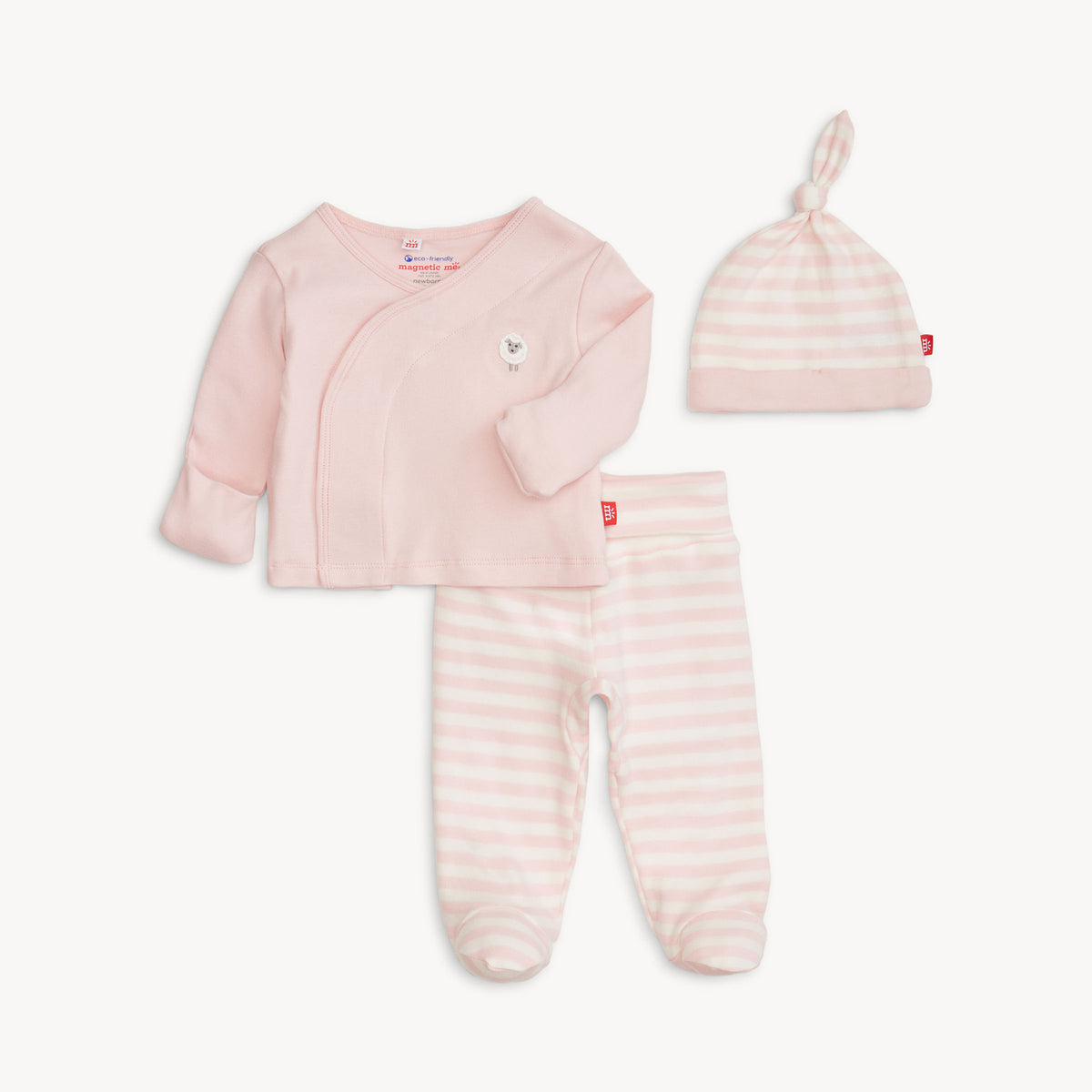 A three-piece baby clothing set in pale pink, including a long-sleeve wrap-style top, footed pants with horizontal stripes, and a matching beanie with a knotted top, laid out on a light off-white background.