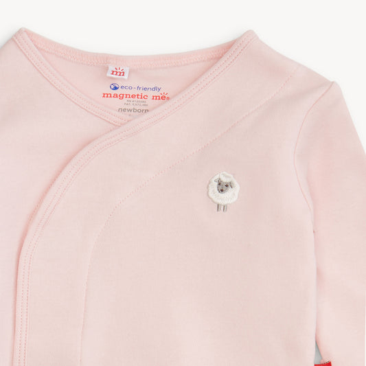 A close-up of a pale pink long-sleeve baby wrap top with a small embroidered sheep face on the chest. The inside neck label shows the Newborn brand and 'eco-friendly magnetic mus' text.