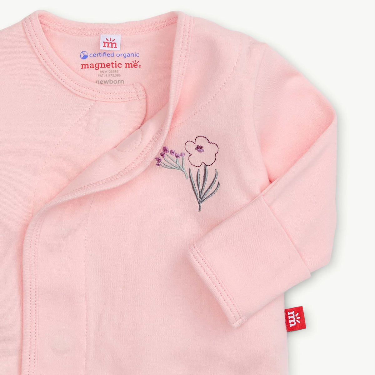 A light pink long-sleeve baby wrap jacket with a floral embroidery on the chest and a red 'magSafe' compatibility tag on the sleeve, shown on a clean white background.