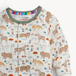 A close-up of a baby long-sleeve sleep shirt with a woodland animal print on an off-white background. The print features brown bears, foxes, raccoons, squirrels, and mushrooms, with a green collar and a colorful striped inner neck lining.