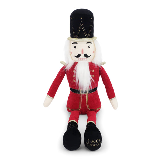 Plush toy resembling a nutcracker in red outfit with black hat on a white background