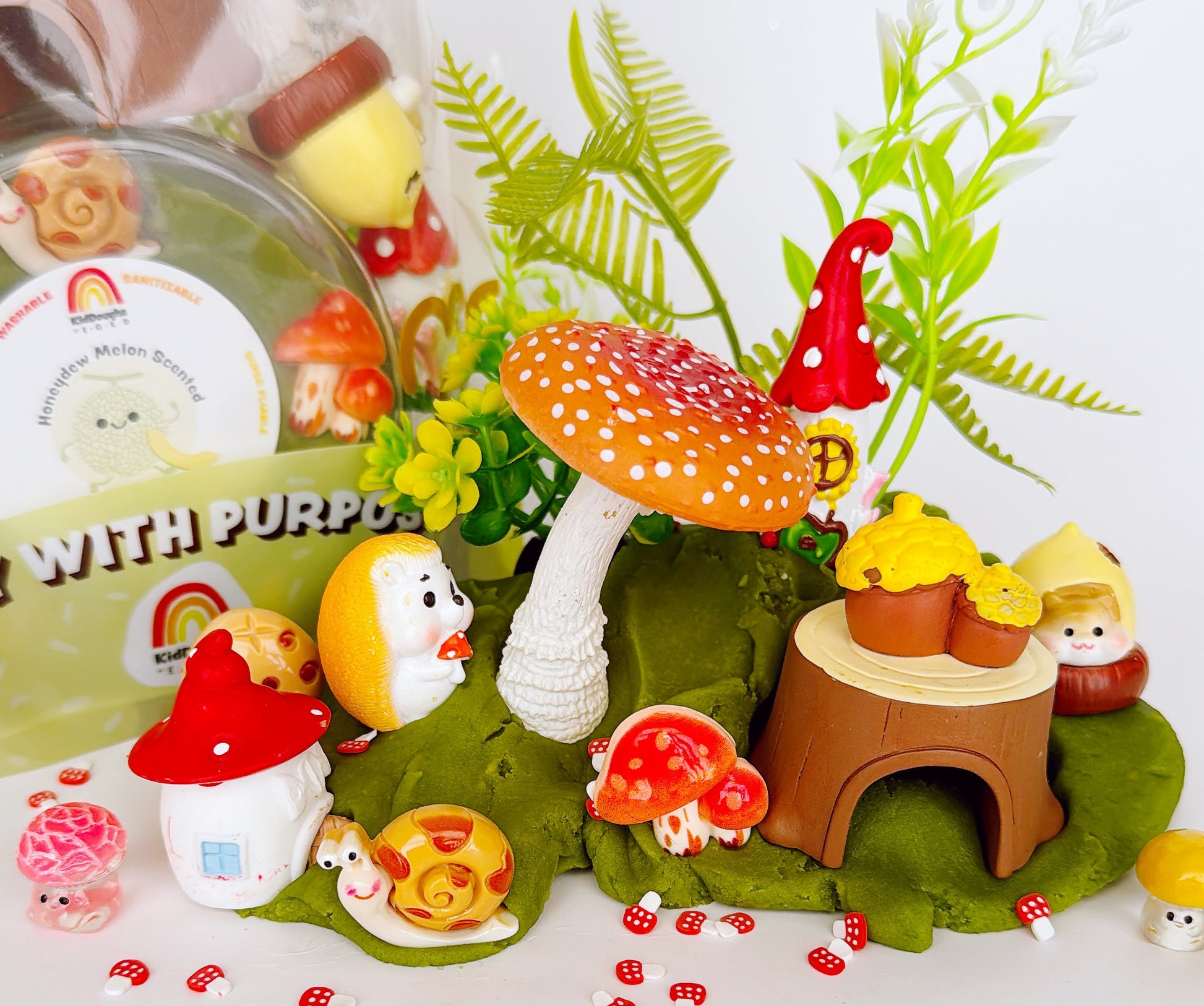 Fairy garden with miniature mushrooms, a snail, and a small house on a white background.