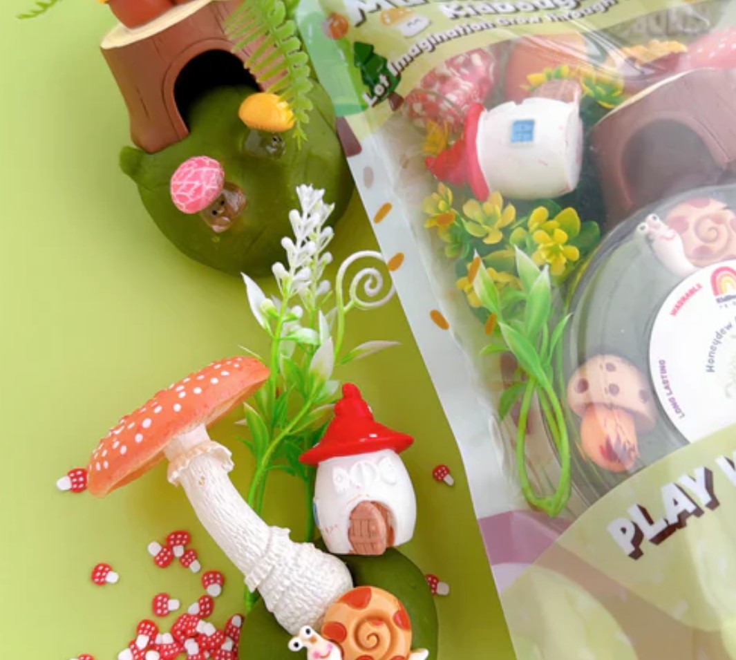 Fairy garden accessories including a small house, mushroom, and gnome on a green background.