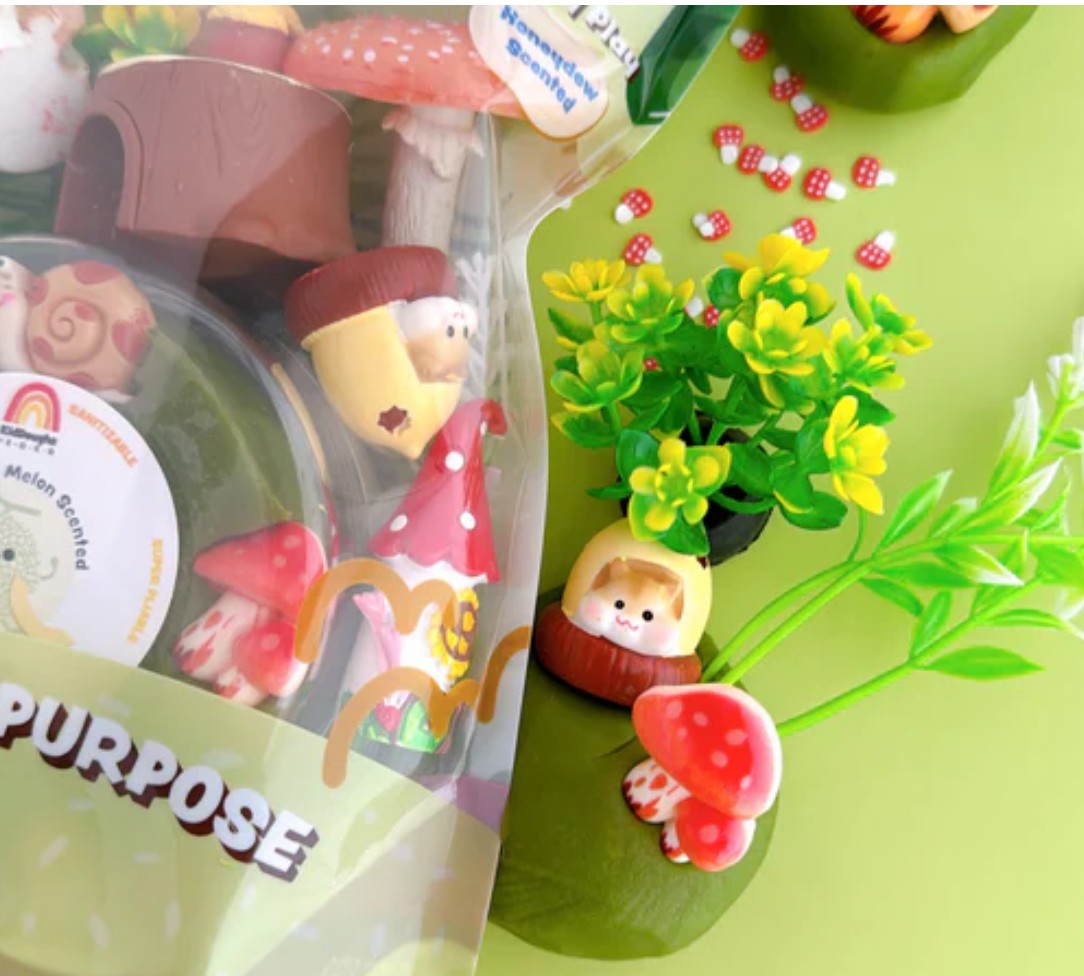 Fairy garden accessories including small figures and plants on a green surface.