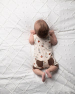 Baby lying on a textured white blanket wearing a patterned outfit.
