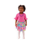 A child model wearing a pink floral print skort set with a matching pink top and white tights.