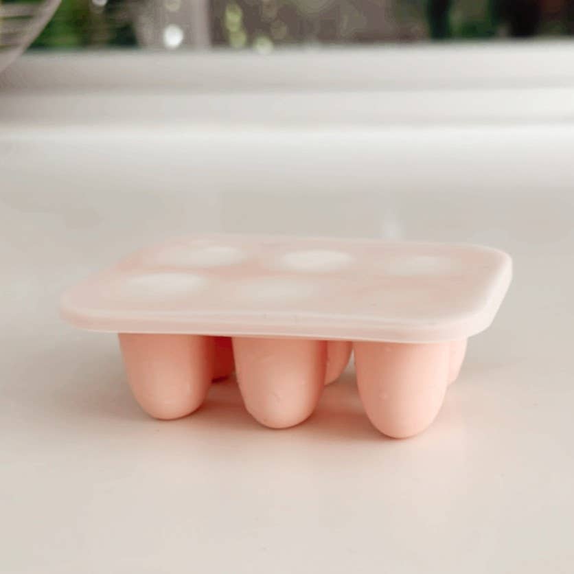Pink silicone self feeding freezer tray on a white surface