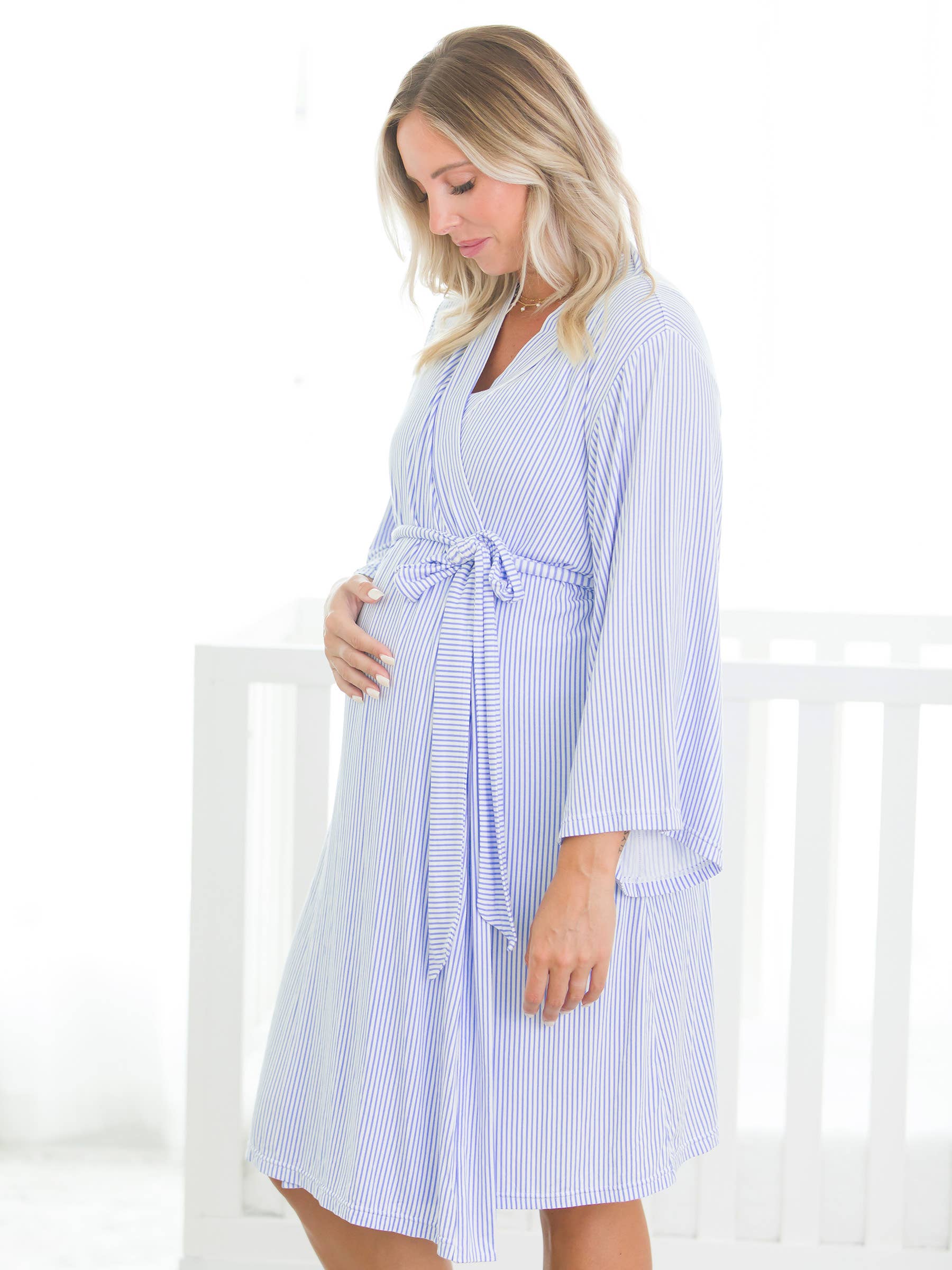Pregnant woman wearing a blue and white striped robe against a white background