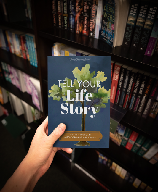 Book titled 'Tell Your Life Story' held in front of a bookshelf.