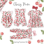 Children's clothing set with cherry pattern on a white background, featuring romper, dress, and leggings.