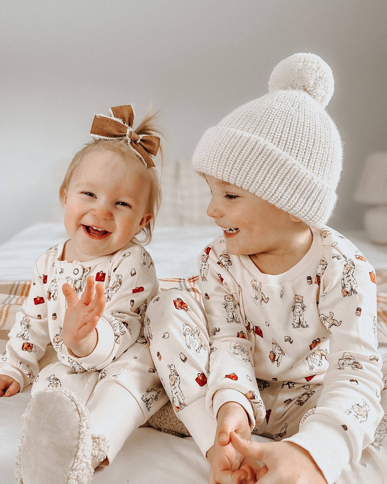 Two children wearing matching Paddington bear pajamas with a neutral background