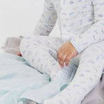 Child wearing a white onesie with blue airplane pattern, sitting on a light blue blanket.