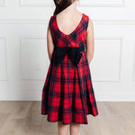 Red plaid dress with a black bow on a white paneled wall background