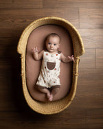 Baby lying in a woven basket on a wooden floor