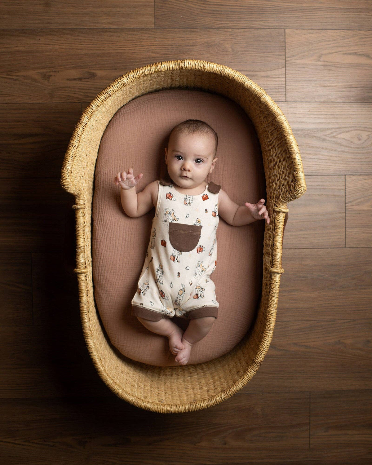 Baby lying in a woven basket on a wooden floor