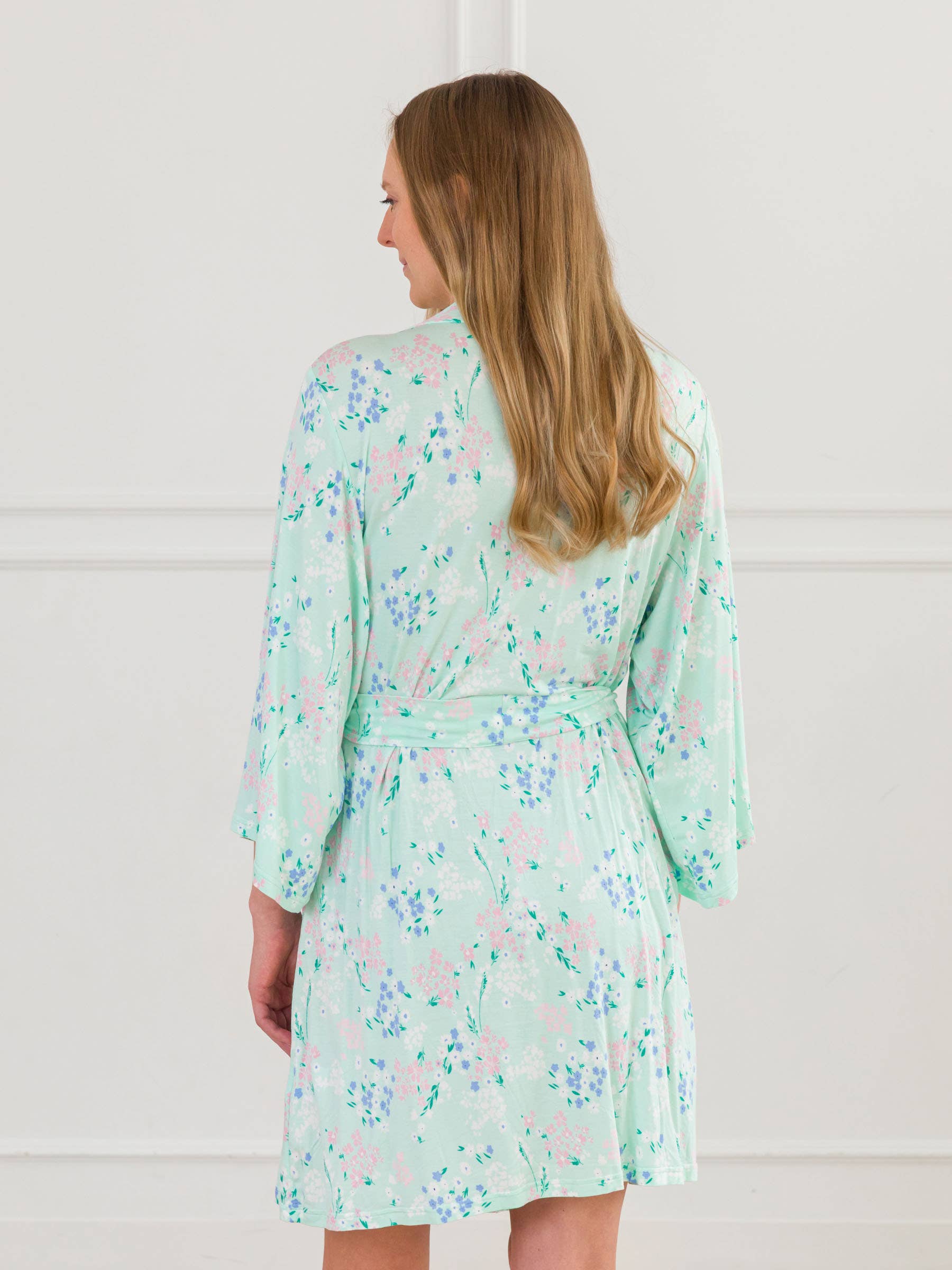 back of Woman wearing a light green floral robe against a white background
