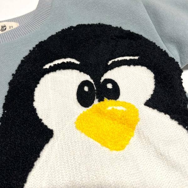 Close-up of a sweater with a penguin design on a light gray background