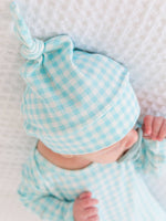 Baby in a blue and white checkered outfit on a white blanket