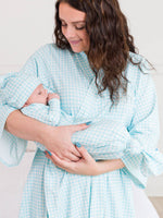 Woman in a light blue checkered robe holding a baby