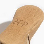 Close-up of a tan leather baby shoe sole with 'FP' branding on a white background