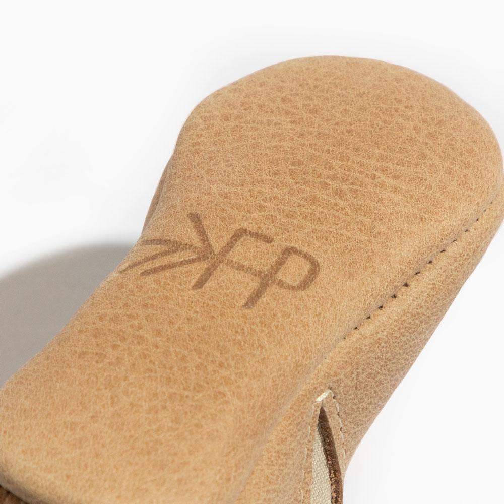 Close-up of a tan leather baby shoe sole with 'FP' branding on a white background