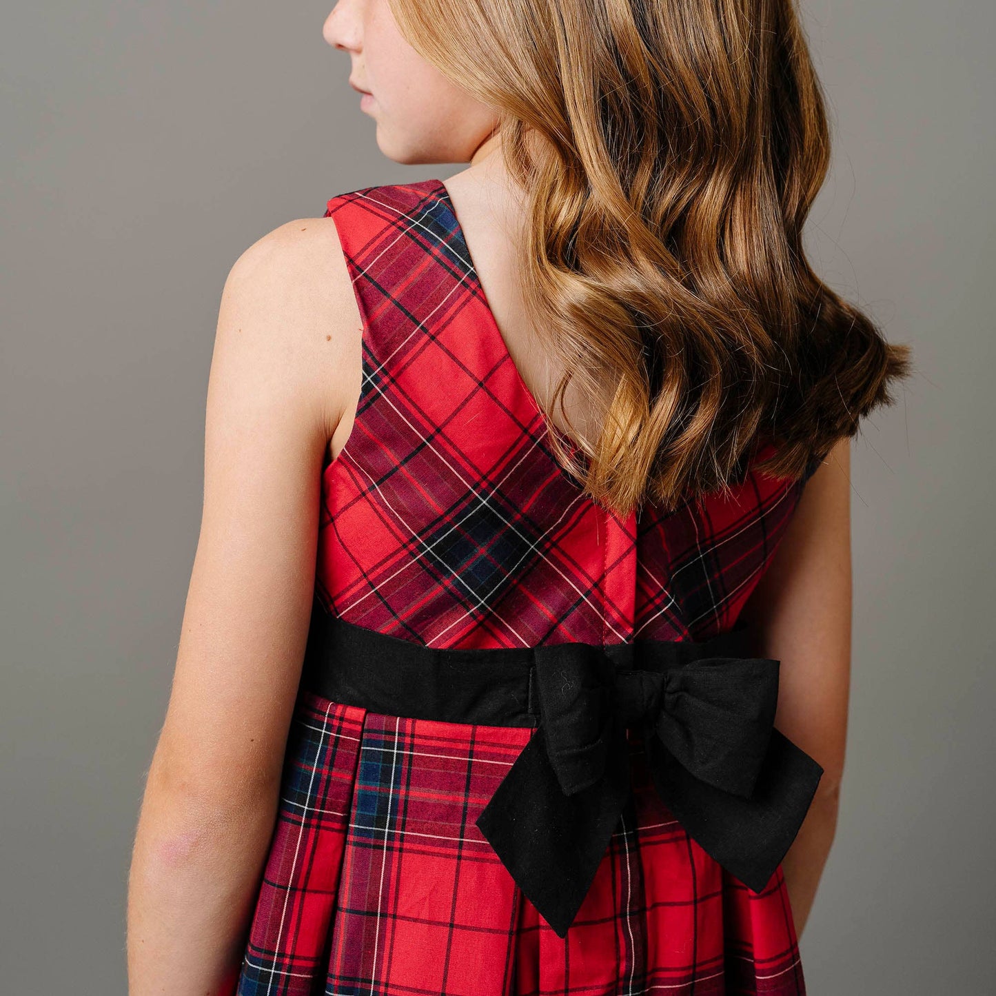 Red plaid dress with a black bow on a plain background