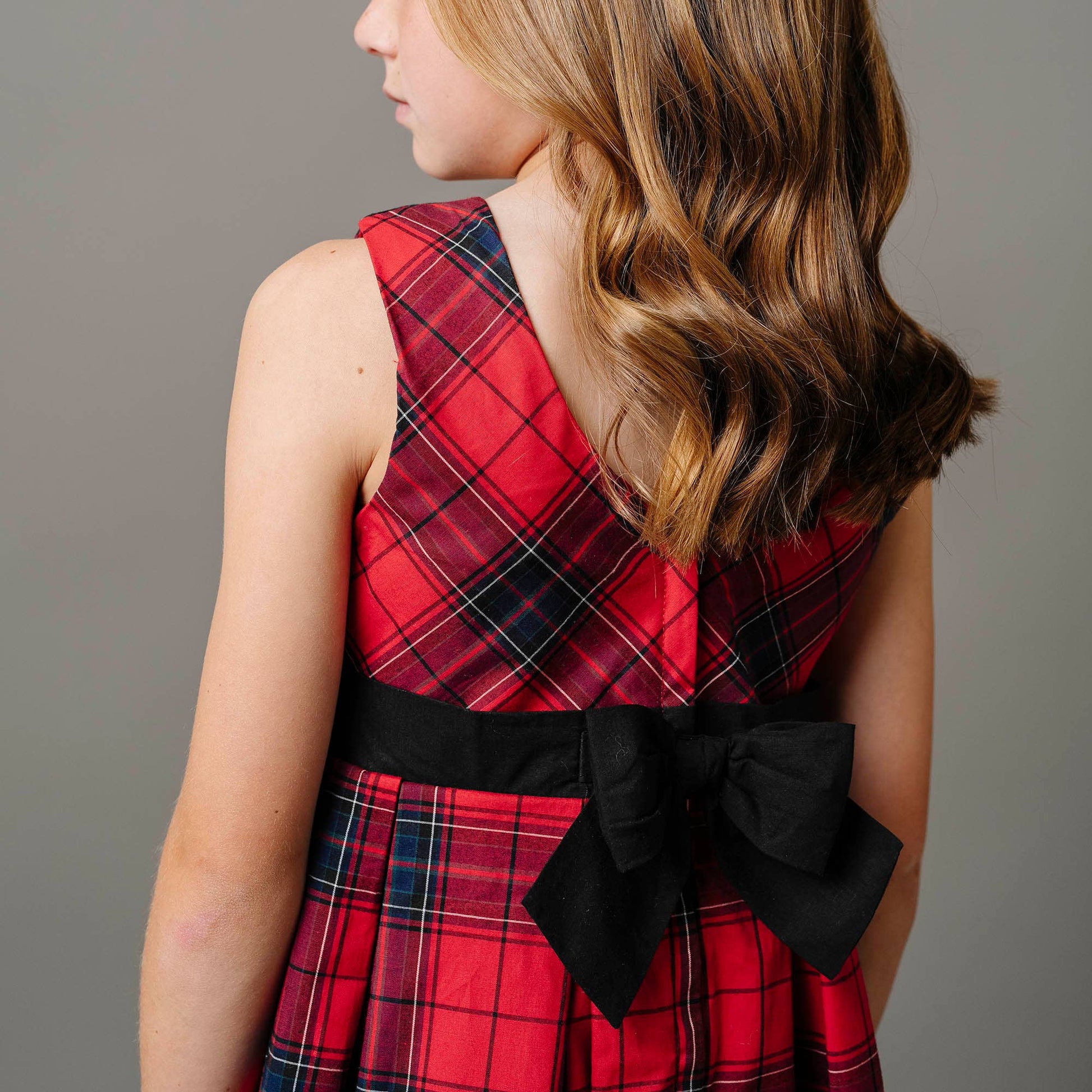 Red plaid dress with a black bow on a plain background