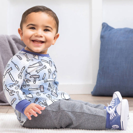 Child wearing 2 piece outfit with tool pattern sitting on a couch