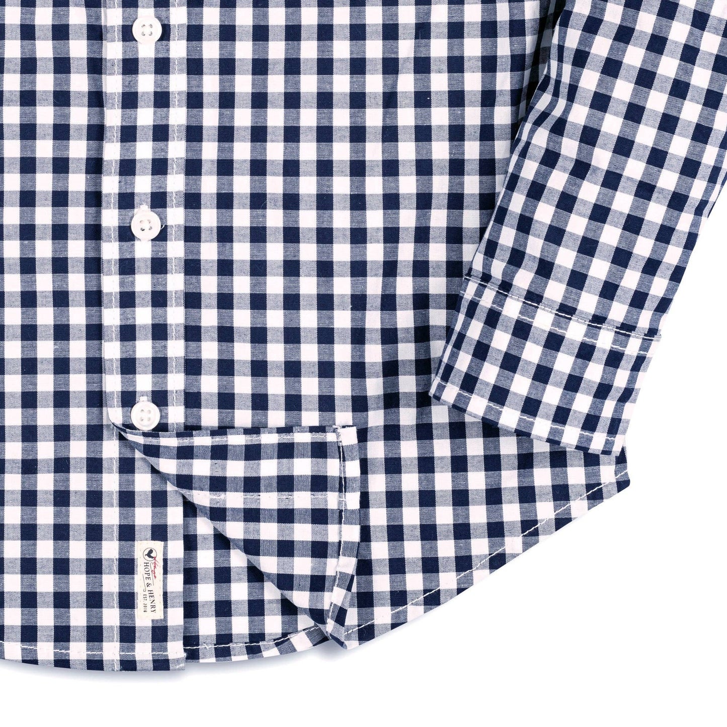 Close-up of a navy and white checkered shirt with rolled-up sleeve on a white background