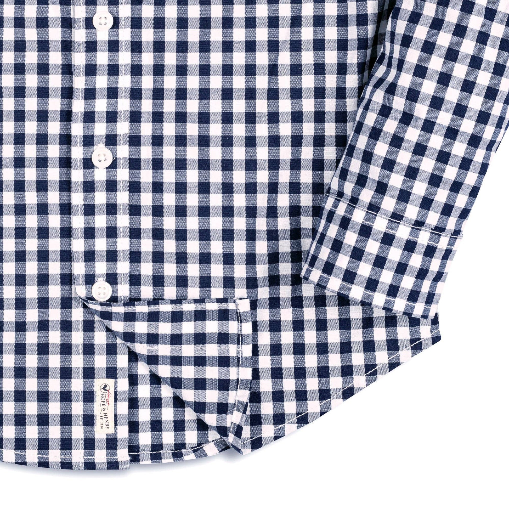 Close-up of a navy and white checkered shirt with rolled-up sleeve on a white background