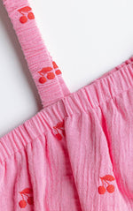 Close-up of a pink dress with cherry designs on a white background