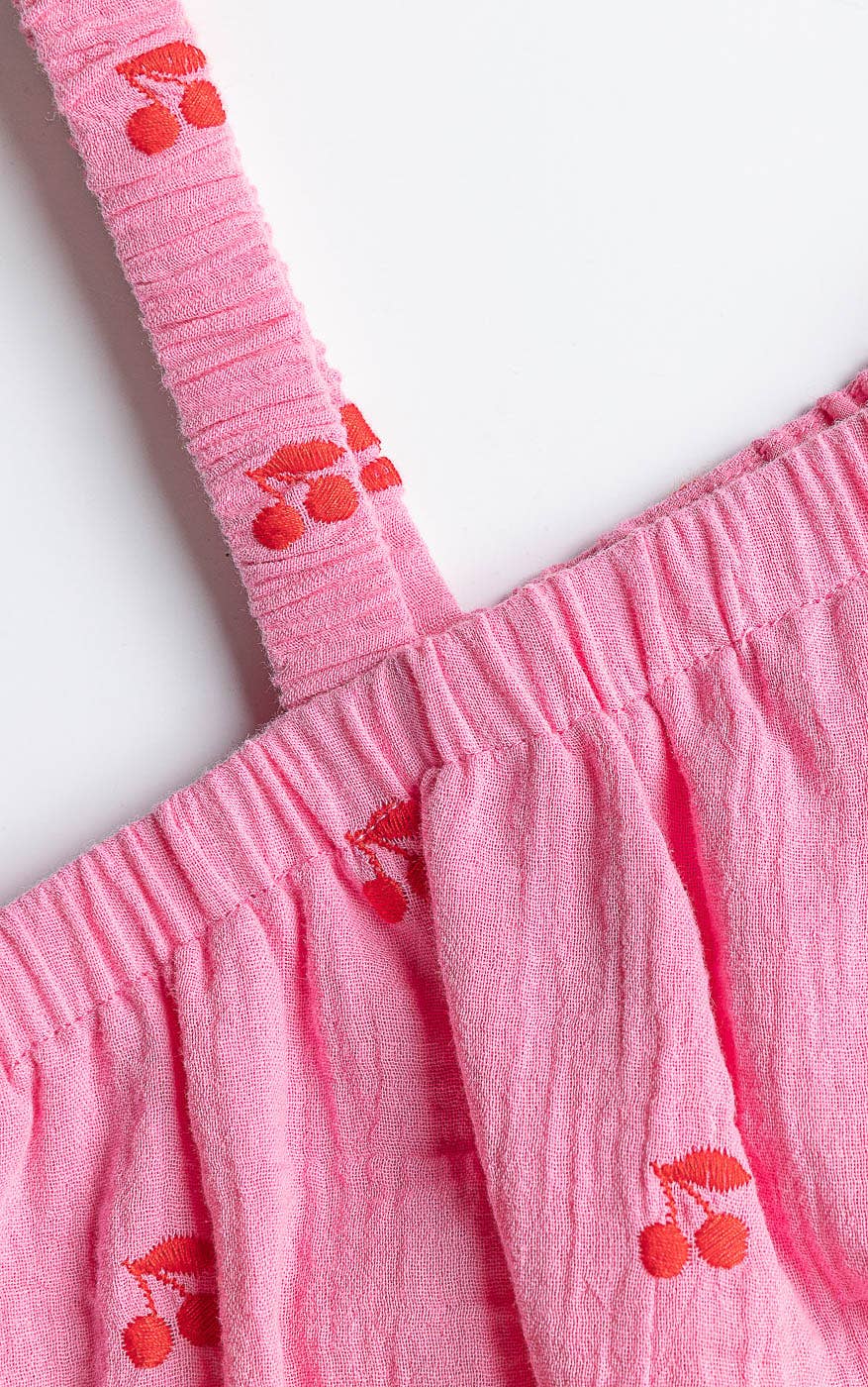 Close-up of a pink dress with cherry designs on a white background